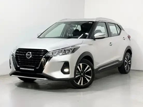 Imagem de um Nissan Kicks prata em showroom, destaque para o design moderno, rodas de liga leve e interior confortável, com preço acessível de até 100 mil reais.
