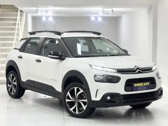 Imagem de um Citroën C4 Cactus branco em showroom, com design moderno, detalhes pretos e teto solar, ideal para quem busca SUV até 100 mil.