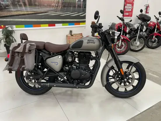 Imagem de uma Royal Enfield Classic 350 com preço até 40 mil reais, exibida em uma loja de motocicletas, com detalhes em preto, cinza e banco em tom de marrom, ideal para quem busca estilo clássico e bom desempenho.