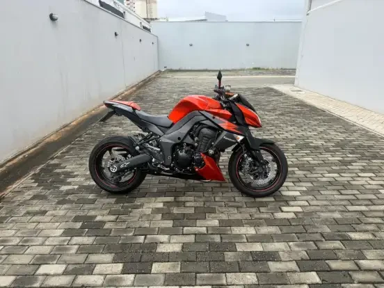 Imagem da motocicleta Kawasaki Z1000 ABS vermelha e preta estacionada em um pátio, ideal para quem busca uma moto esportiva até 40 mil reais.