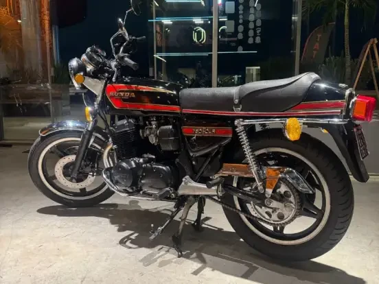 Imagem de uma Honda CB 750 Four preta clássica, com detalhes vermelhos, em excelente estado, ideal para colecionadores e amantes de motos antigas, aproximadamente com 100 mil quilômetros rodados.