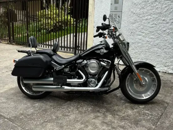 Imagem de uma Harley-Davidson Softail Fat Boy preta estacionada na rua, ideal para quem busca motocicleta de alto desempenho e estilo clássico até 100 mil.
