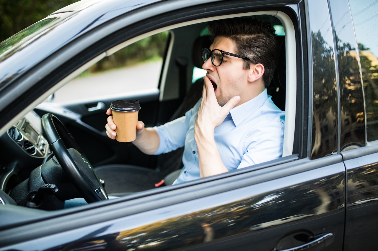 Young Man Drink Coffee Feeling Tired And Yawning While Driving A Car