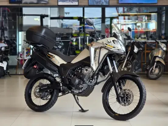 Honda XRE 300 Sahara preta e branca, motocicleta de aventura com bagageiro traseiro, ideal para quem busca uma moto até 50 mil reais.