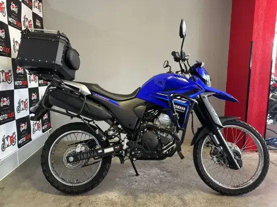 Imagem de uma Yamaha XTZ 250 Lander azul com bagageiro traseiro, ideal para aventuras off-road, disponível por até 50 mil reais.