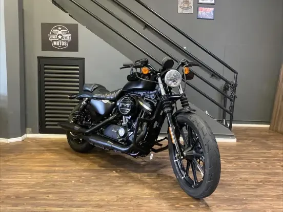 Imagem de uma Harley-Davidson Sportster Iron 883 preta em uma loja, com design clássico e preço acessível até 50 mil reais, ideal para quem busca uma moto robusta e estilosa.
