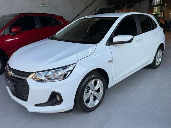 Imagem de um Chevrolet Onix branco estacionado em uma loja, com design moderno, elegante e ótimo para quem busca um carro compacto e econômico.