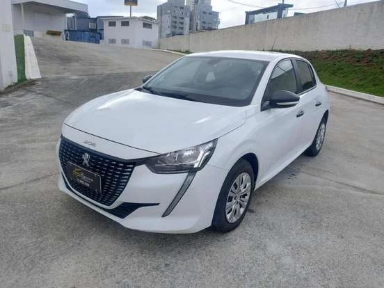 Imagem de um Peugeot 208 branco estacionado em uma área urbana com prédios ao fundo, destacando seu design moderno e eficiente. Ótima escolha para quem busca um carro compacto e econômico.