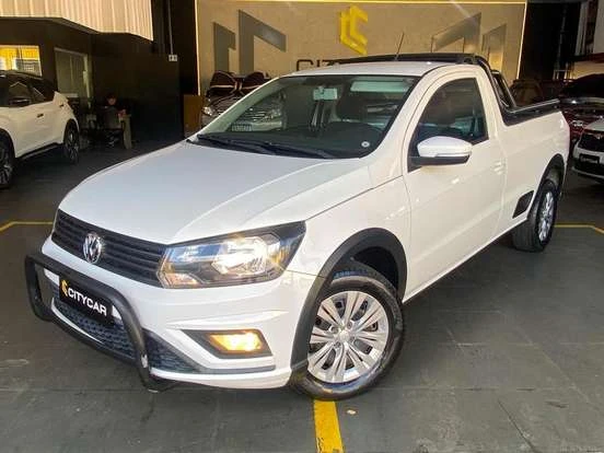 Volkswagen Saveiro branca estacionada em showroom, destaque para seu design compacto e funcional, ideal para trabalho e uso urbano, com acabamento bem conservado.