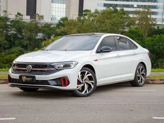 Volkswagen Jetta branco em uma rua na cidade, com fundo de prédios e árvores, destaque para o design moderno e esportivo, ótimo custo-benefício até 280 mil.