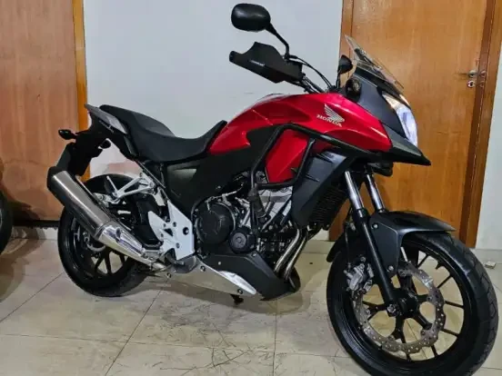 Imagem de uma Honda CB 500X vermelha, moto de alta performance com design robusto e pneus grandes, ideal para até 100 mil km de uso.