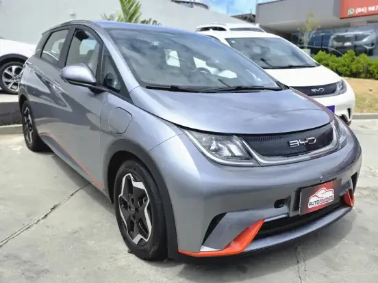 Imagem do BYD Dolphin em destaque na loja, com design moderno e detalhes em laranja nas rodas e para-choque, visando vendas até 170 mil reais.